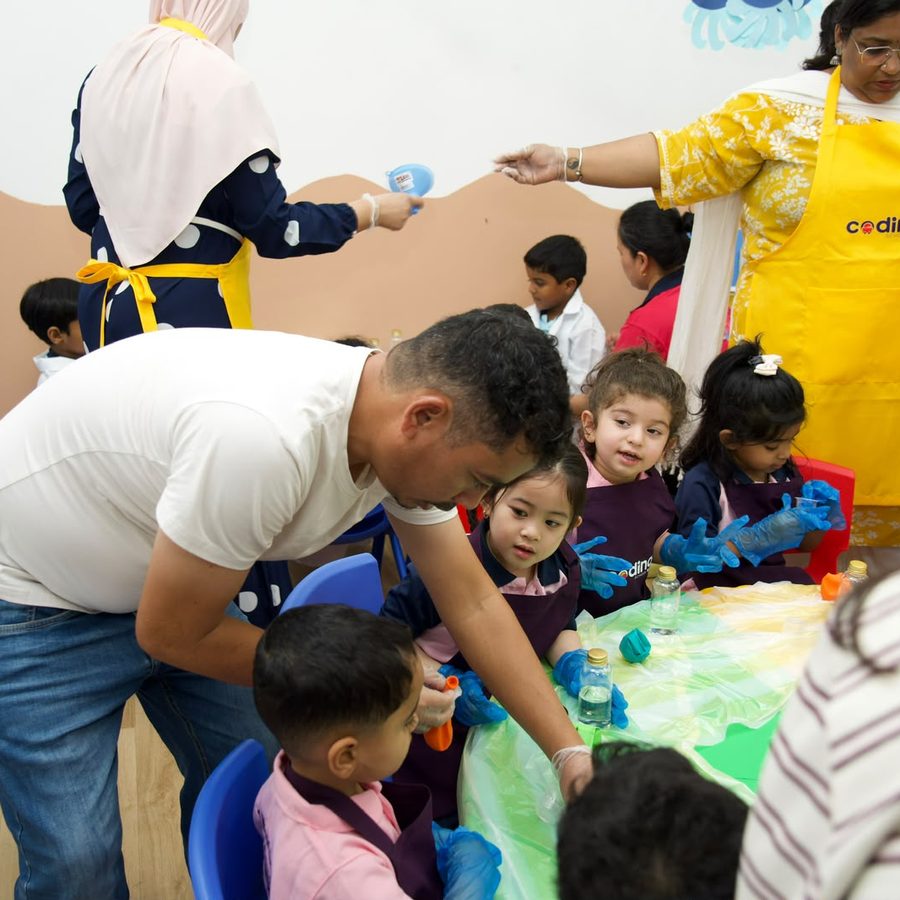 A facilitator leaning in to guide children through a hands-on activity.