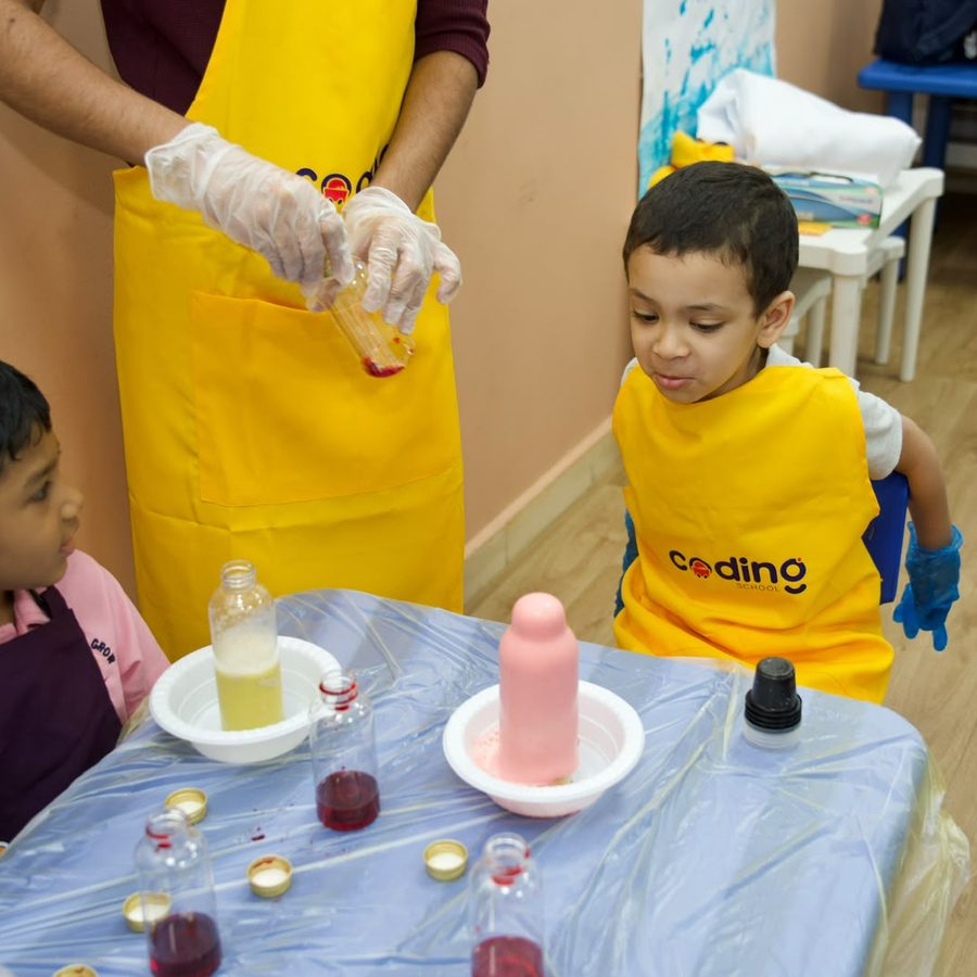 A facilitator helping a child pour a reaction that foams up at the experiment booth.